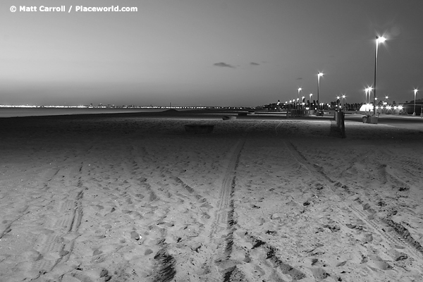 black and white illuminated beach at night looking toward Long Beach skyline