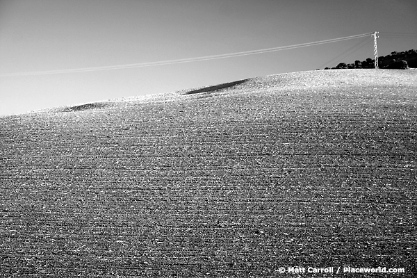 black and white plowed hillside with powerlines