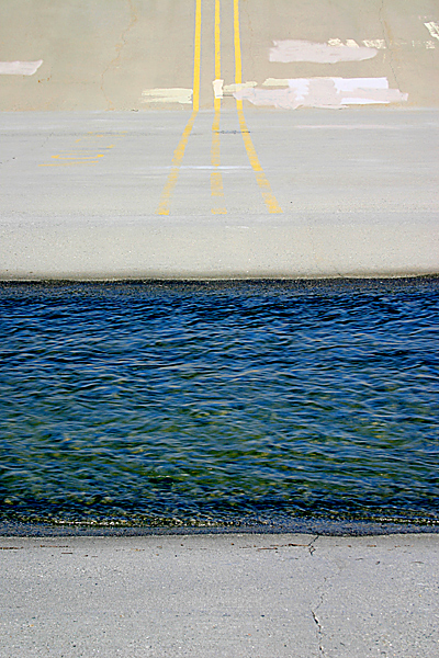 water flowing over concrete with yellow stripes painted on it